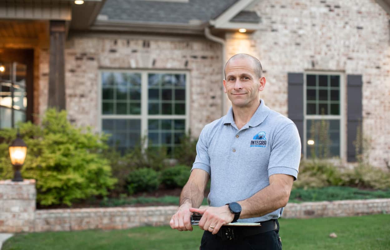 Home Inspector Todd Thuss standing in front of home and holding a clipboard