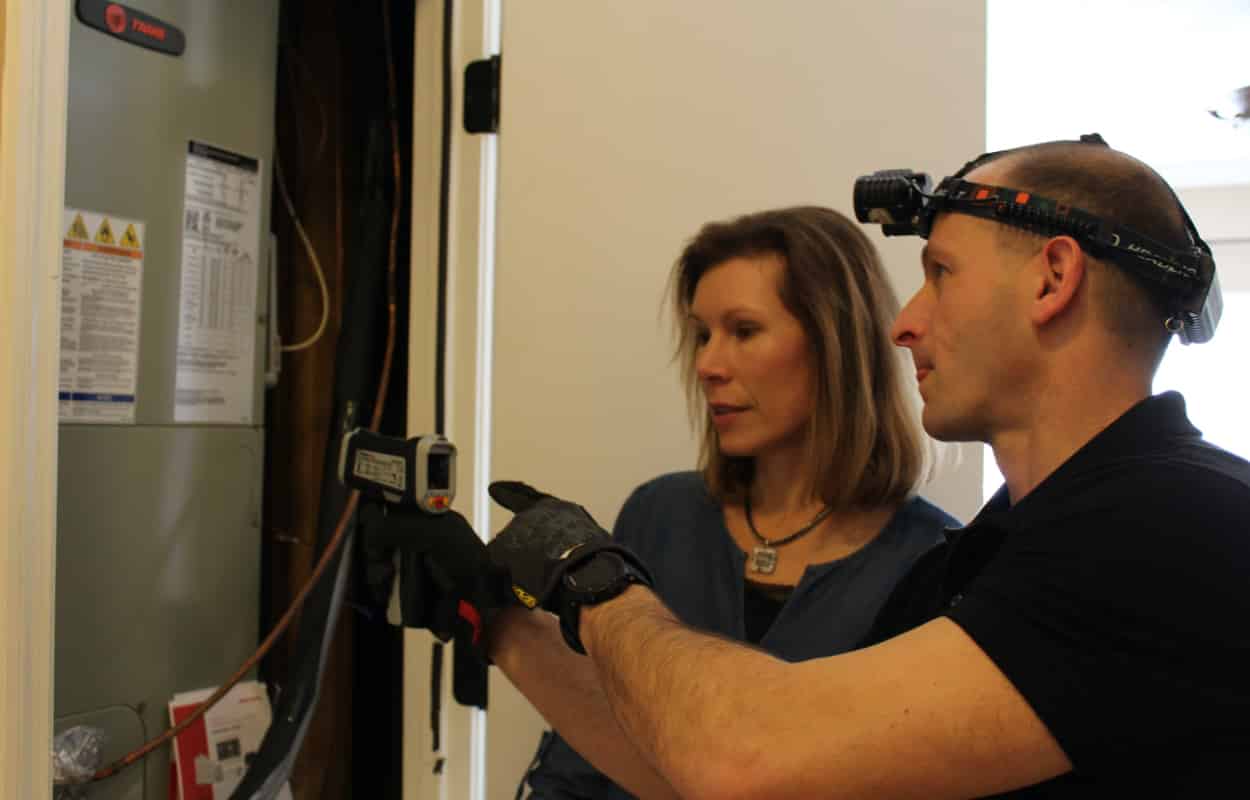 Photo of Inspector Todd Thuss inspecting an HVAC unit with a client