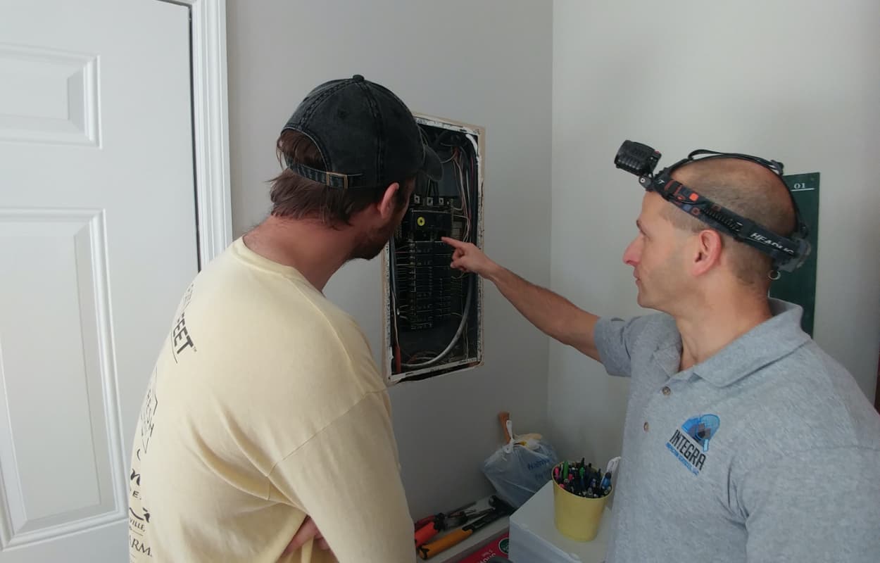 Certified Home Inspector Todd Thuss inspecting an electrical panel with a client