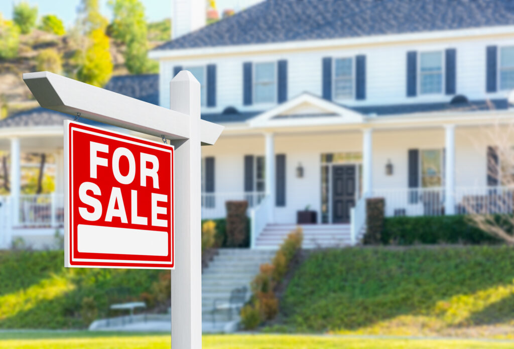 Photo of a house with a real estate For Sale sign out front