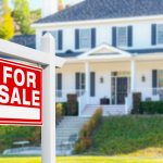 Photo of a house with a real estate For Sale sign out front